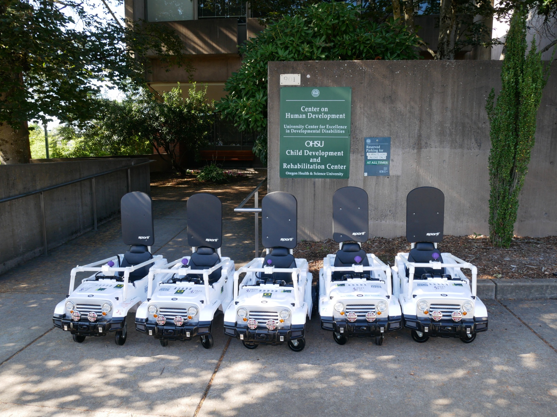 A fleet of five white Wayfinder™ jeeps lined up outside the OHSU Child Development and Rehabilitation Center.